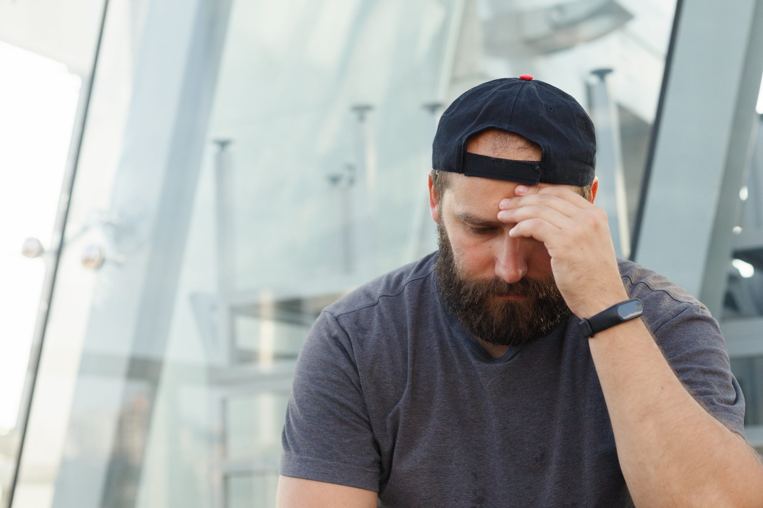 man with untreated alcoholism sits with his head resting on his hand