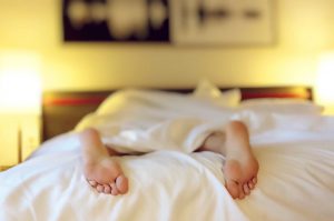 Man asleep with feet hanging off the bed