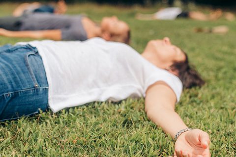people laying on a grassy field with their arms out