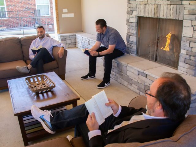 Three men reading about sobriety in Nashville men's rehab.